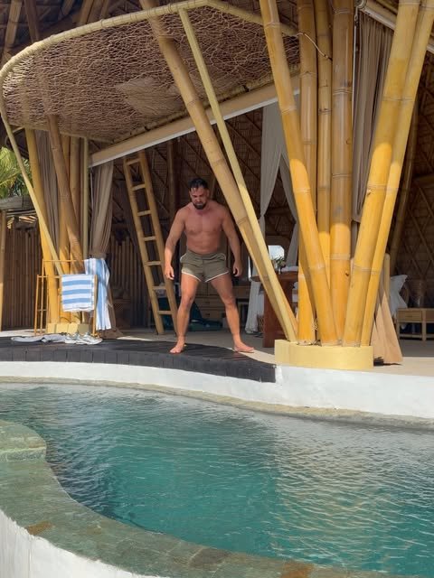 Addam Sattar at the edge of a pool in a bamboo pavilion