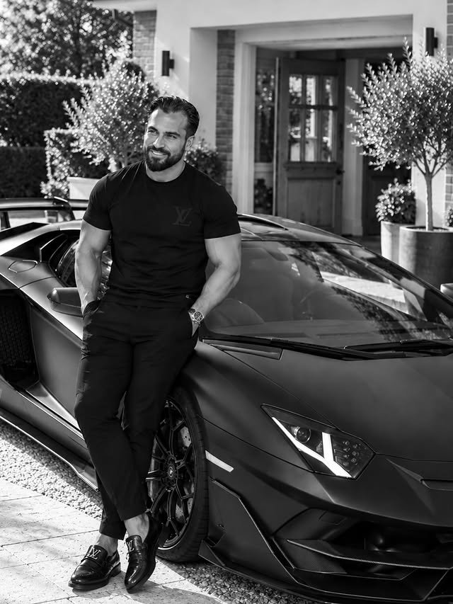 Addam Sattar in black, beside a black Lamborghini